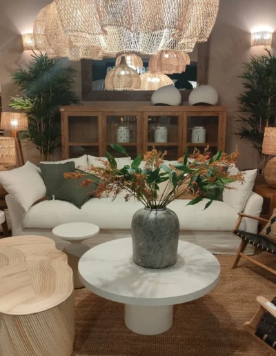 Decoración de salón de estilo mediterráneo con sofá blanco, mesas de centro de diseño, gran mueble aparador de madera y lámparas de techo de mimbre trenzado.